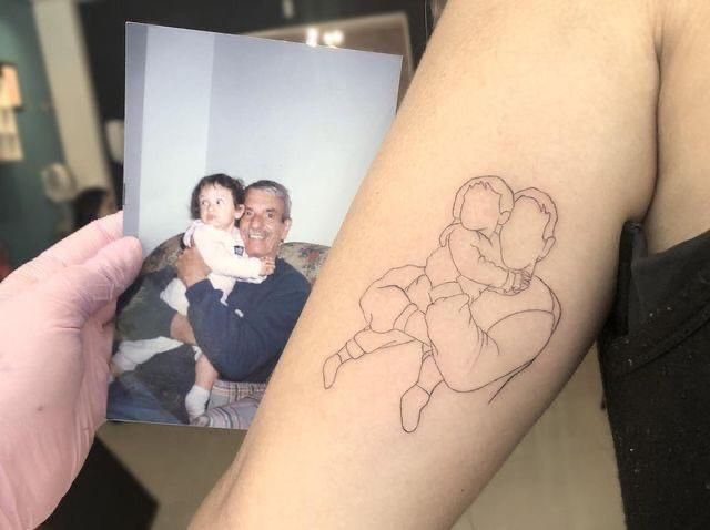 a man holding a small tattoo with a drawing of a woman and child on his arm