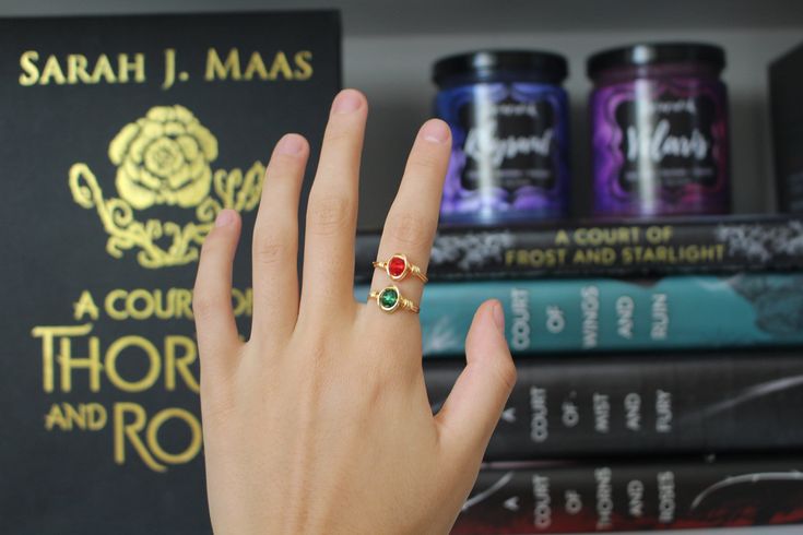 a person's hand with a ring on it next to some books and other items