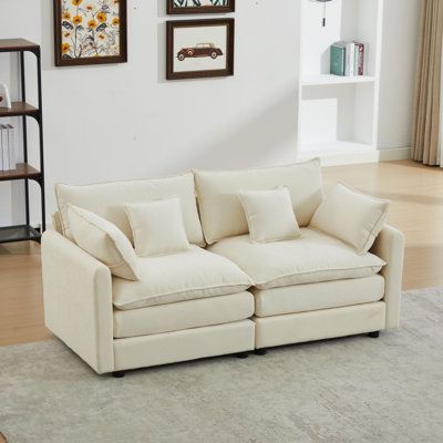 a living room with white furniture and pictures on the wall