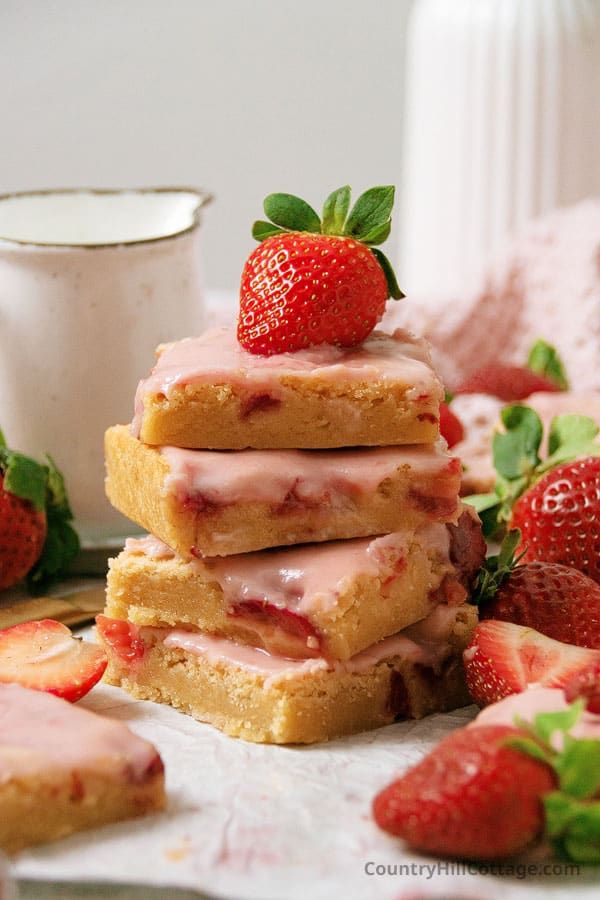 strawberry shortbreads stacked on top of each other next to strawberries and milk