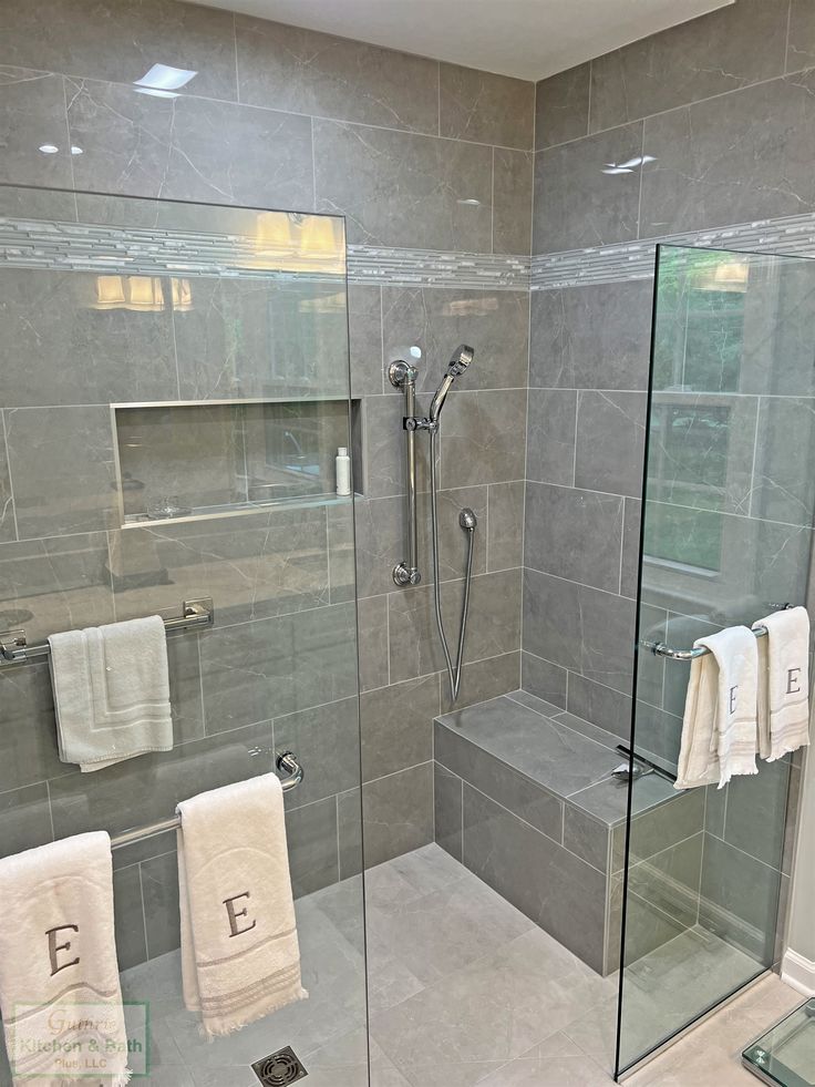 a walk in shower sitting next to a glass enclosed shower stall with two towels hanging on the wall