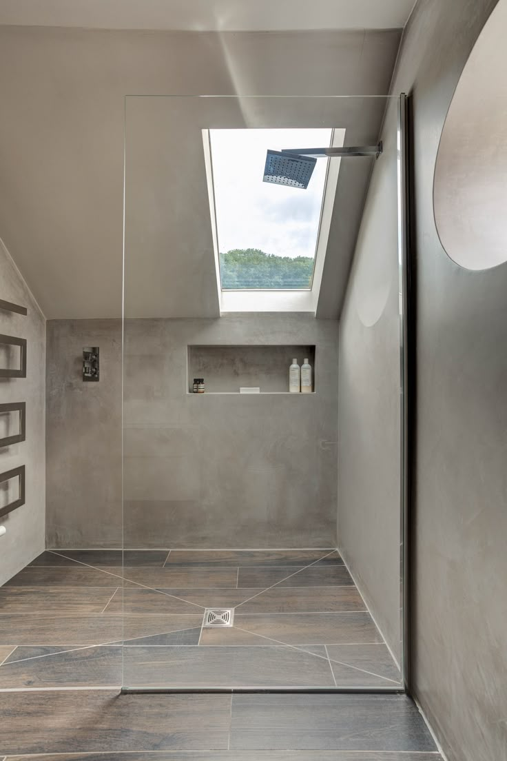 a bathroom with a skylight above the shower and tile flooring on the walls