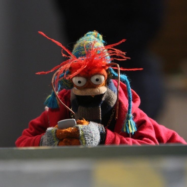 a stuffed animal with red hair and blue eyes sitting on top of a wooden table