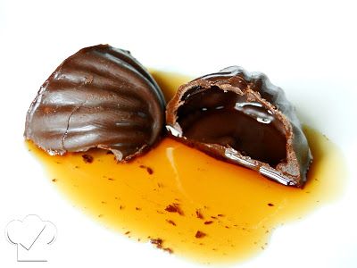 two pieces of chocolate covered in caramel sauce on a white surface, one half eaten