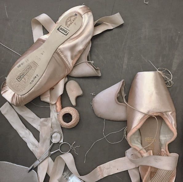 several pairs of ballet shoes are laying on the floor next to some thread and scissors