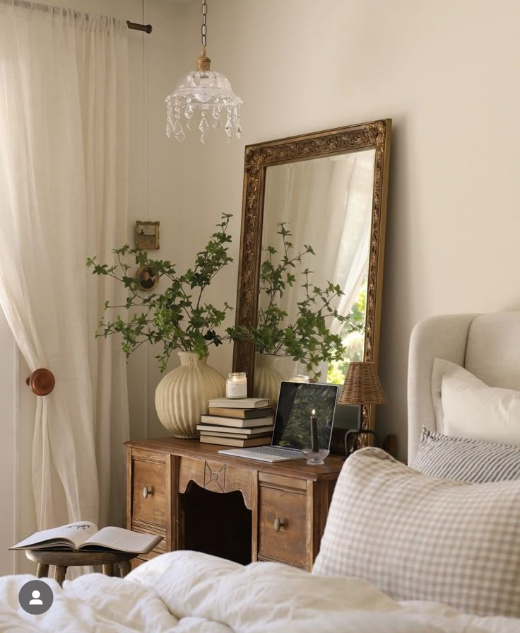 a bedroom with a bed, mirror and plants on the table in front of it