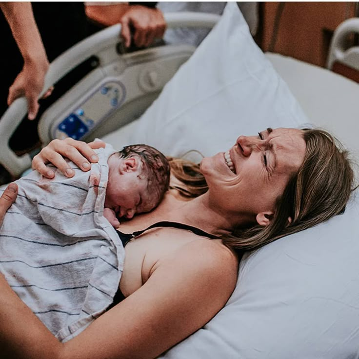 a woman holding a baby in a hospital bed