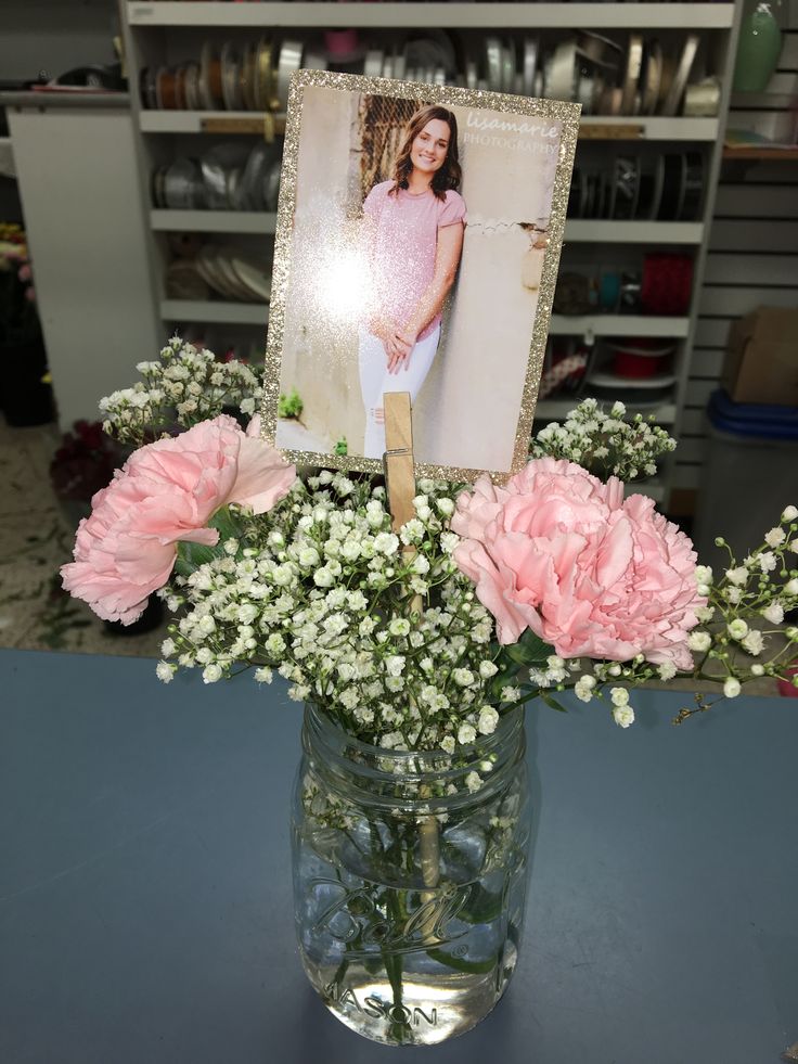 a vase filled with pink flowers and baby's breath in front of a photo