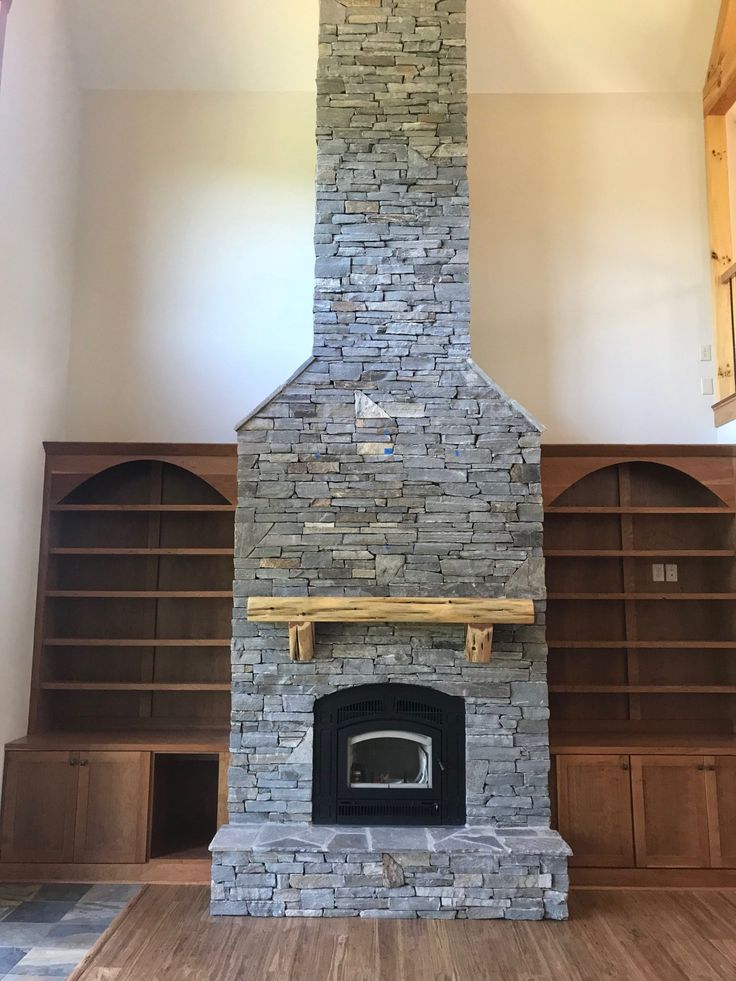 an empty room with a stone fireplace in the center