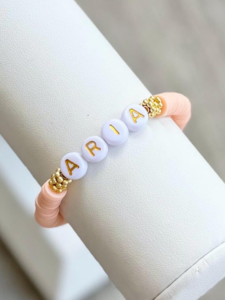 a white bracelet with gold letters on it