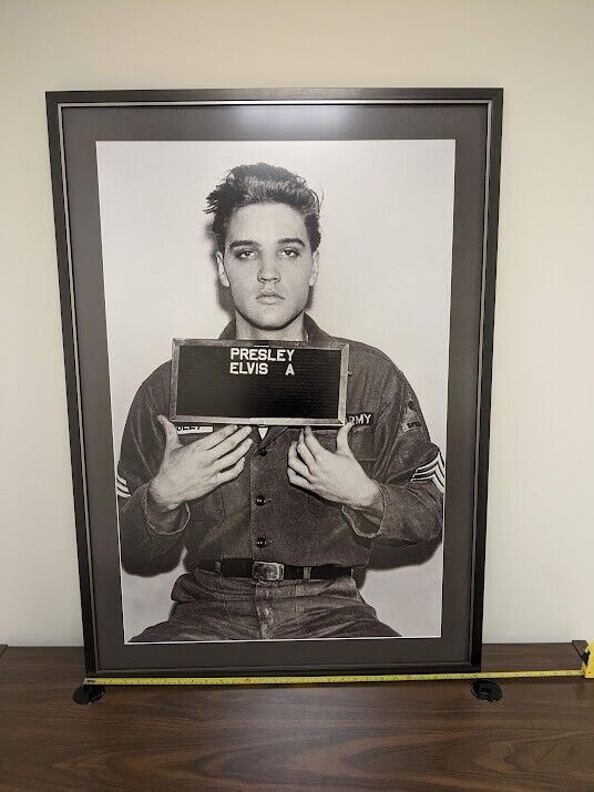 a black and white photo of elvis presley holding a sign in front of a police poster