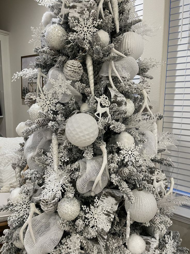 a white christmas tree decorated with silver ornaments