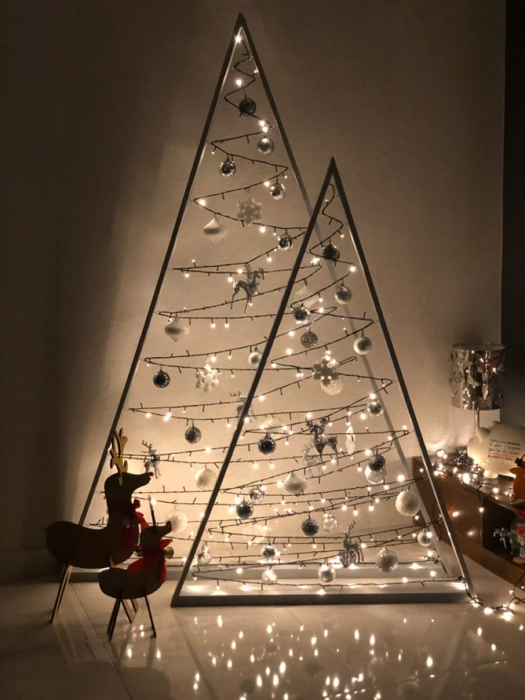 a christmas tree with lights on it and a chair next to it in front of the wall