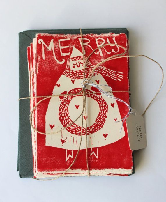 a red and white christmas card wrapped in twine on top of a green book