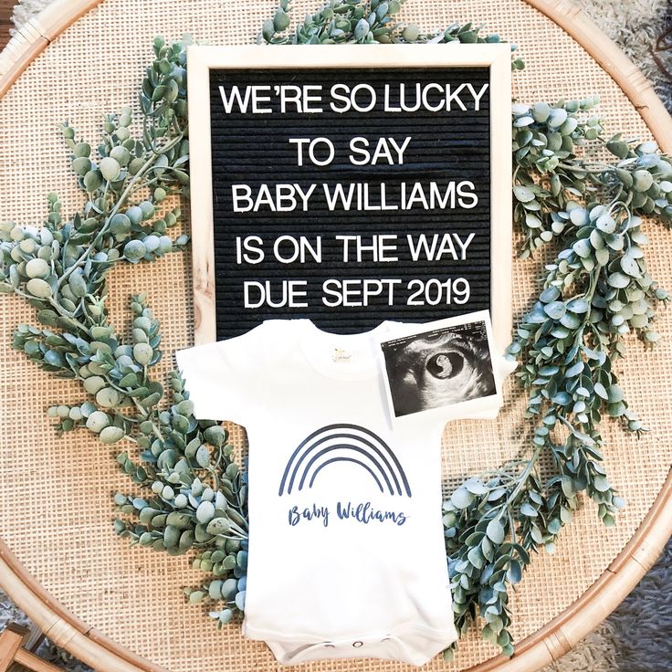 a baby's t - shirt is on display in front of a sign that reads, we're so lucky to say baby williams is on the way duee