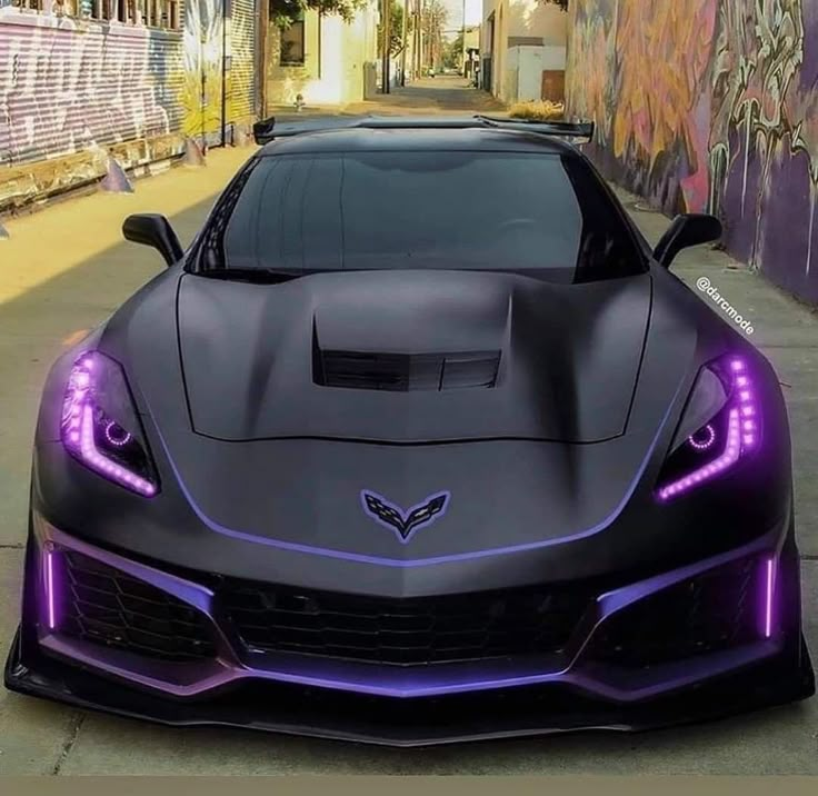 a black sports car with purple lights on it's hood parked in front of a graffiti covered wall