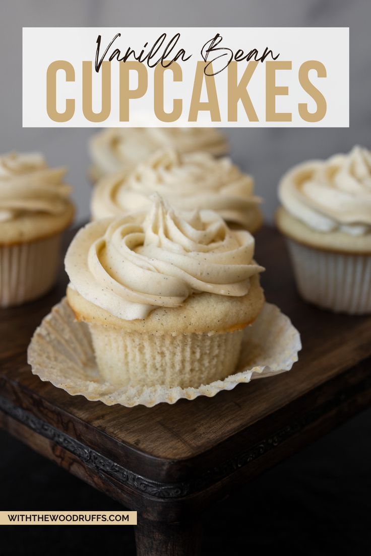 cupcakes with vanilla frosting sitting on a wooden tray