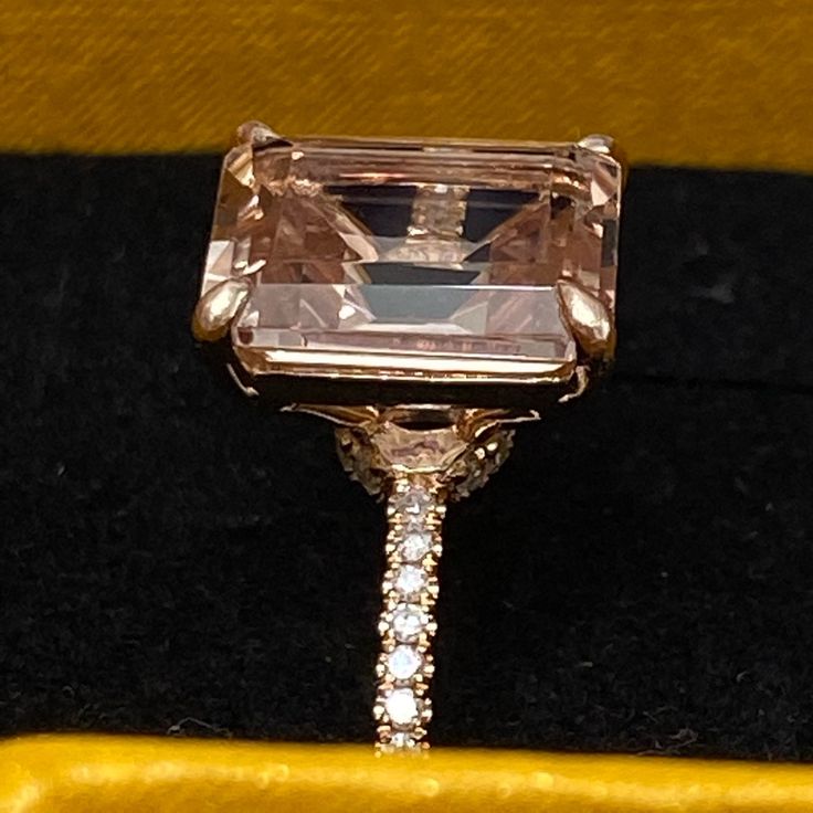 an engagement ring with a pink diamond in the center on a velvet box that is yellow and black