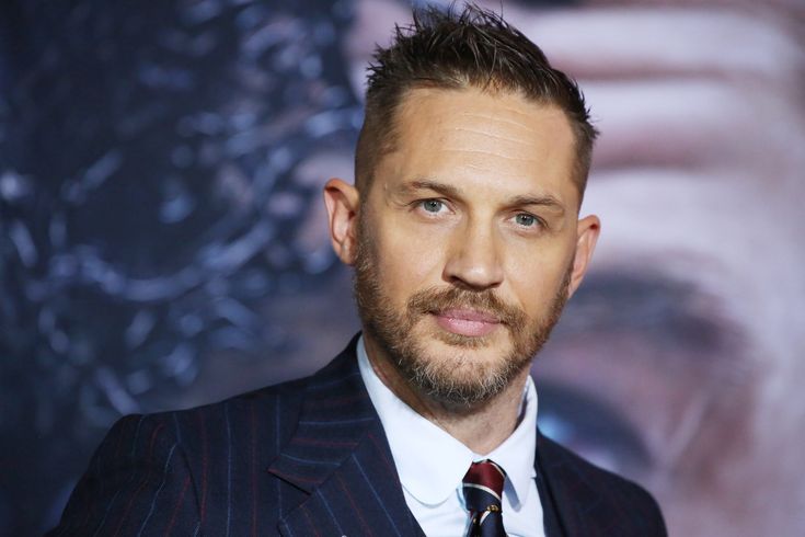 a man wearing a suit and tie in front of a poster