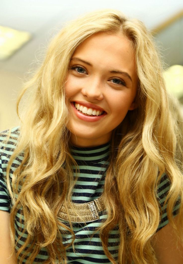 a woman with long blonde hair smiling at the camera