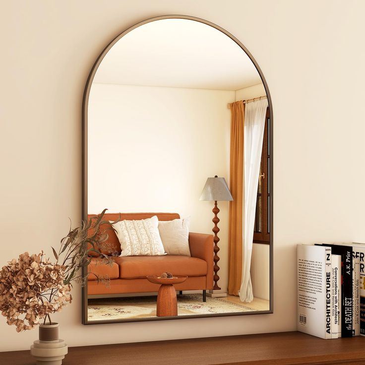 a mirror sitting on top of a wooden shelf next to a vase with flowers in it