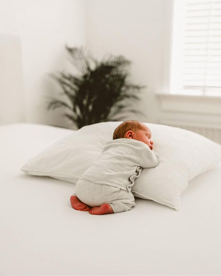 a baby sleeping on top of a white pillow