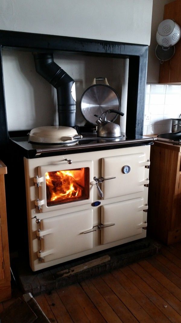 an old fashioned stove in the middle of a kitchen with wood flooring and cabinets