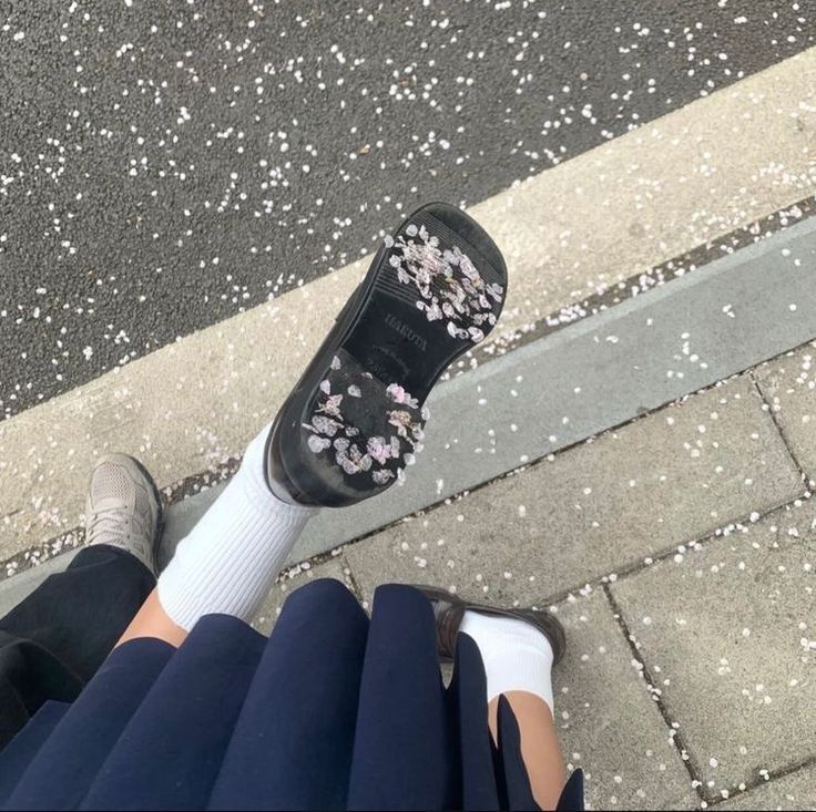 a person standing on the sidewalk with their feet up and wearing high heeled shoes