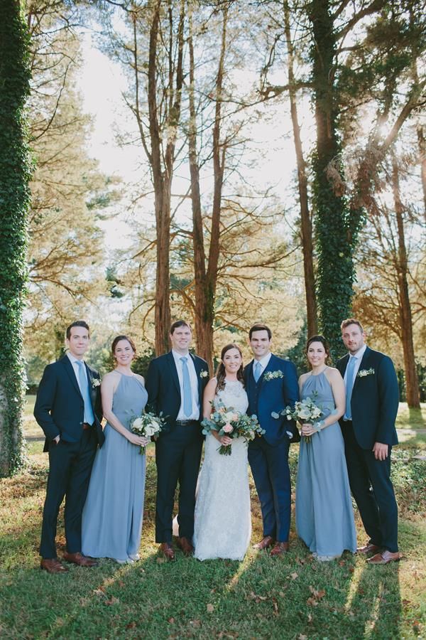 a group of people standing next to each other in front of some trees and grass