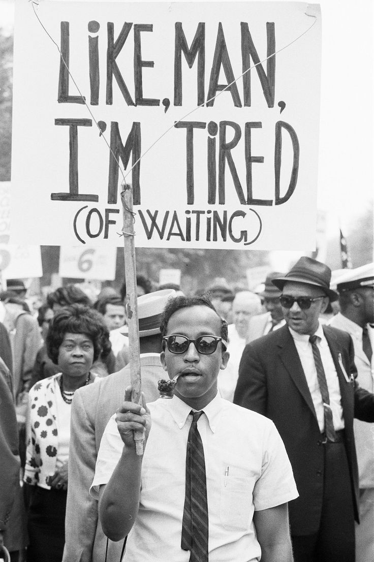 a man holding a sign that says like man, i'm tired of waiting