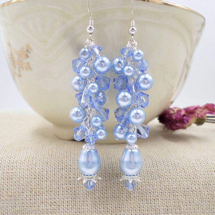 This pair of special earrings was artfully designed and hand crafted by ME in my Wisconsin USA studio.  If you want a unique pair of statement earrings you have come to the right place!  This pair of Light Blue earrings is made with genuine top quality name brand Elements brand crystals and pearls in Light blue and Light Sapphire Blue.  The pearls are round and pear shaped, and the crystals are done in the bicone shape.  Each pearl and crystal has been hand wired into place by me.  The earrings Blue Drop Earrings For Bridal Gift, Handmade Light Blue Jewelry For Party, Blue Bridal Drop Earrings As A Gift, Adjustable Blue Pearl Drop Jewelry, Blue Dangle Bridal Earrings Gift, Elegant Light Blue Beaded Dangle Earrings, Blue Chandelier Drop Earrings For Anniversary, Blue Chandelier Earrings For Party, Handmade Blue Pearl Drop Earrings