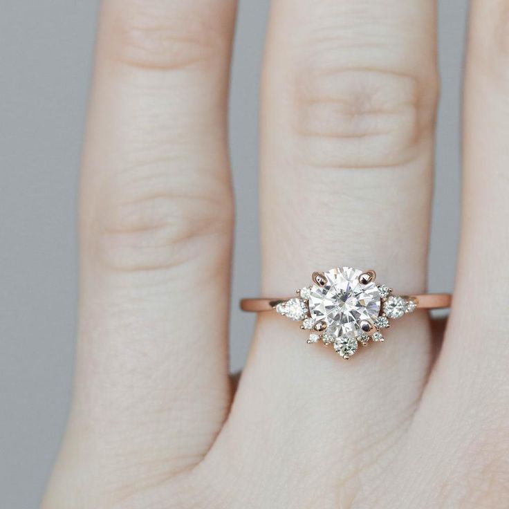 a woman's hand with a diamond ring on her left hand and an engagement band