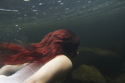 a woman with red hair is swimming in the water