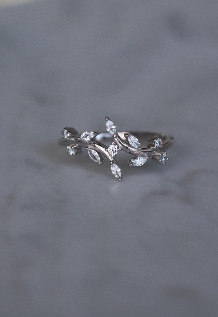 a close up of a ring with leaves on the front and back, sitting on a table