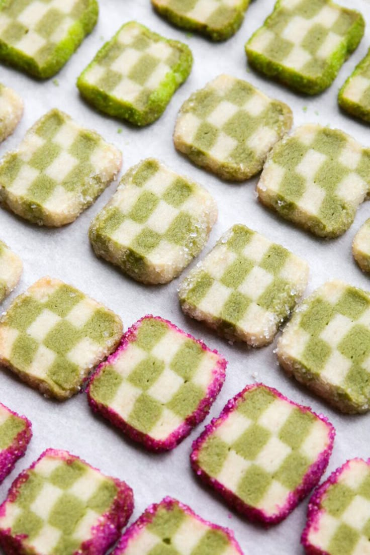 green and pink cookies are arranged on a baking sheet