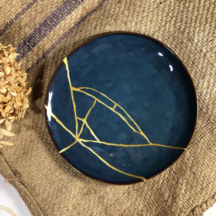 a blue plate sitting on top of a table next to dried flowers and a napkin