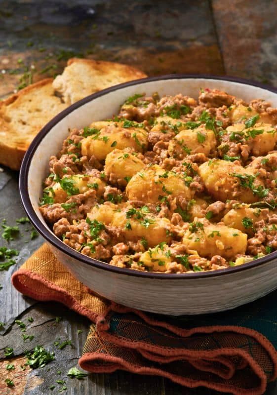 a bowl filled with meat and bread on top of a table