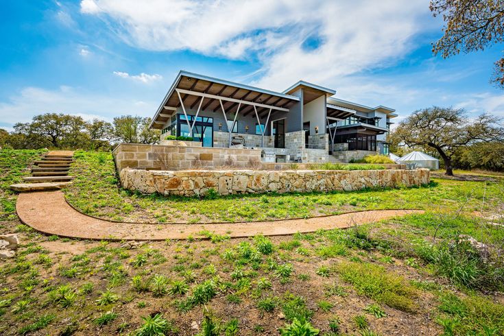 a large house sitting on top of a lush green field next to a stone wall