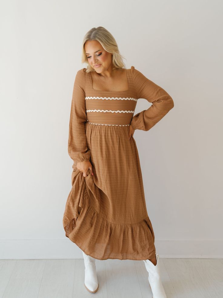 Twirl around in the "Wynn Dress!" This elevated maxi dress is perfect for church or work because of its modest design and fall color! It boasts a soft waffle print fabric, mocha base with ivory rick-rack along the bust, and long balloon sleeves. Easy to pair with boots or heels to complete the look! Detailed Fit: Square neckline maxi dress Cinching at top of shoulder Tie at back of neckline Zipper in the back Waffle pattern throughout skirt Double-lined Overfall Fit: Fitted through bust with a r Brown Fall Maxi Dress For Brunch, Brown Maxi Dress For Fall Brunch, Long Sleeve Brown Maxi Dress For Spring, Brown Ruffled Maxi Dress For Spring, Brown Flowy Maxi Dress For Spring, Brown Modest Maxi Dress For Summer, Flowy Brown Maxi Dress For Spring, Fitted Cream Maxi Dress For Fall, Modest Midi Dress With Square Neck