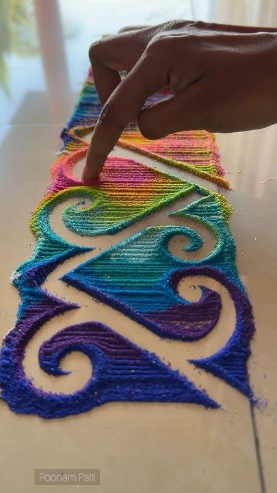 a hand is pointing at an art project on the floor with colored yarn and crochet