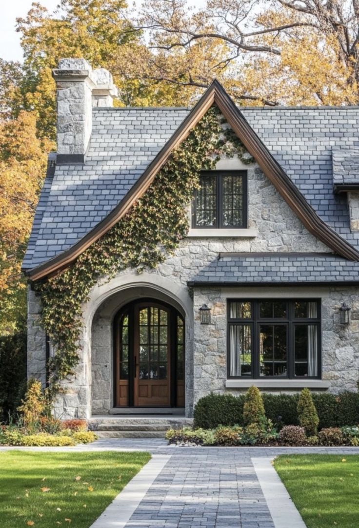 a stone house with ivy growing on the roof and front door, surrounded by lush green grass