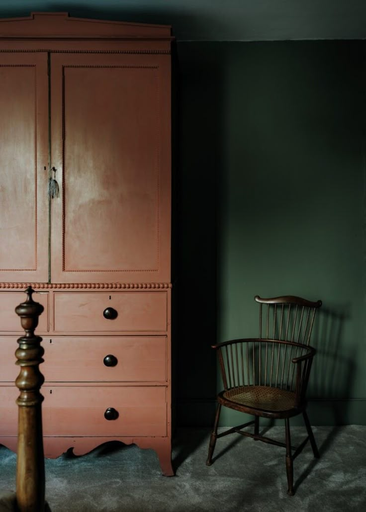 an old armoire next to a chair in a room with green walls and carpet