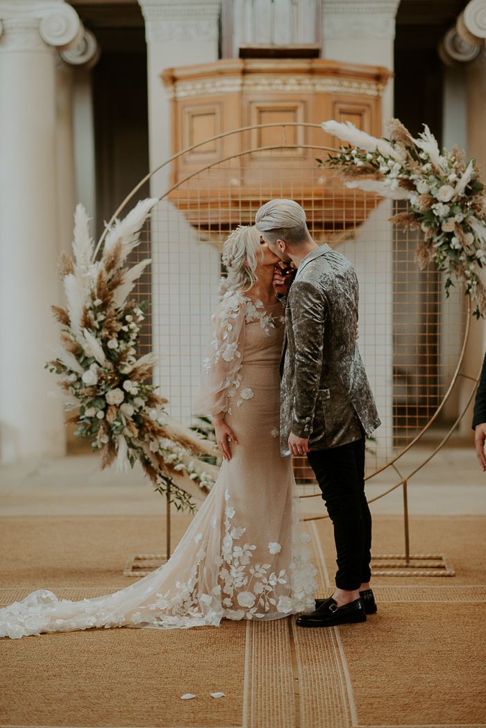 a man and woman standing next to each other in front of a wedding ceremony arch