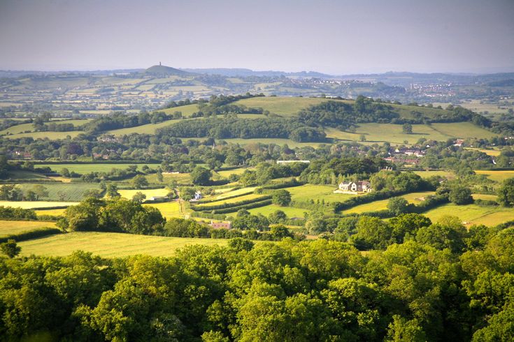 an aerial view of the countryside with green trees and rolling hills in the foreground