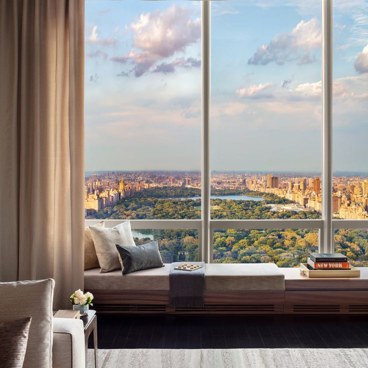 a living room filled with furniture and large windows overlooking a cityscape in the distance