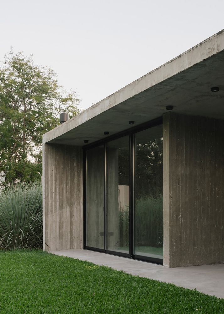 an empty concrete building with large windows and grass