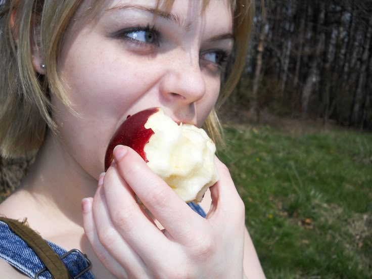 a woman eating an apple in the park