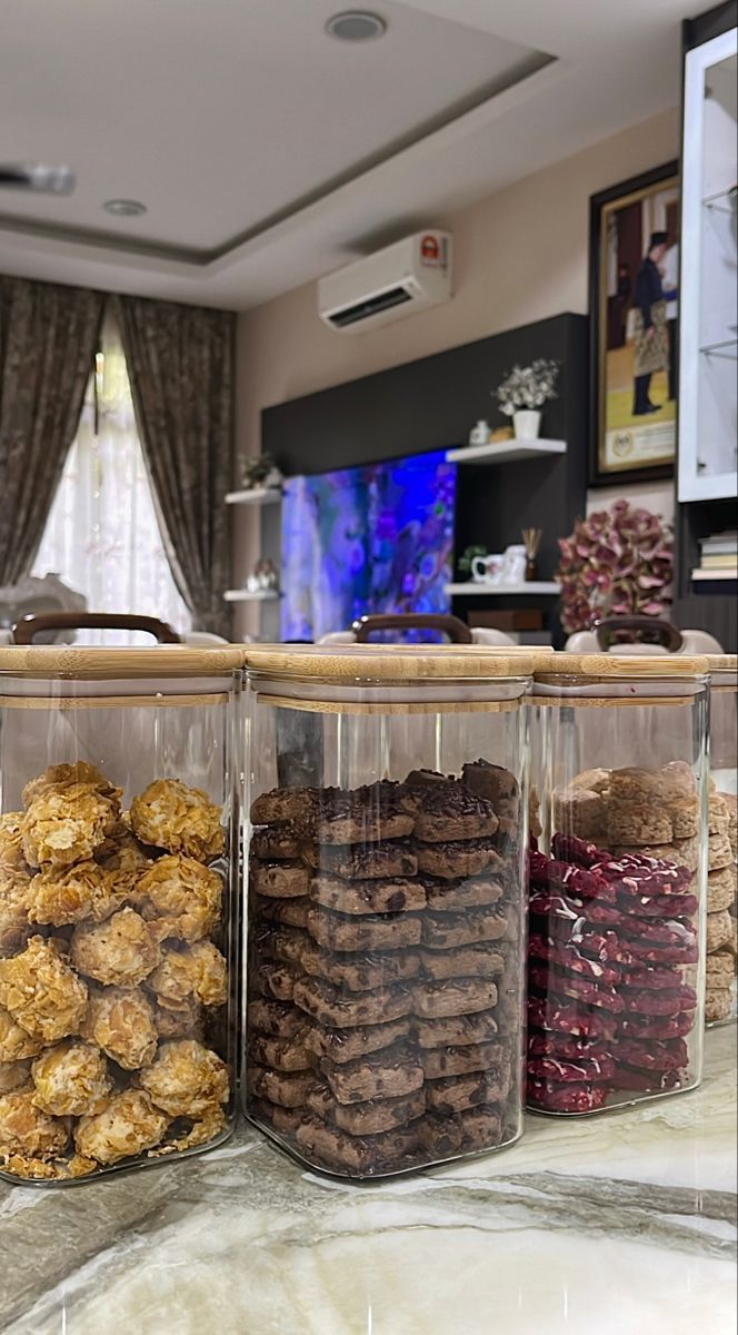 three clear containers filled with cookies on top of a counter