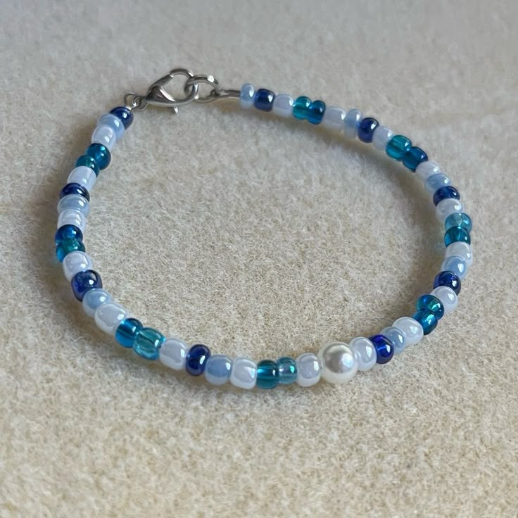 - One Of A Kind Beaded Bracelet - Featuring White, Light Blue, Dark Blue, And Translucent Blue Seed Beads, And White Pearl Center - Silver Colored Hardware - Clasps Closed. No Stretch. - Size/ Circumference Is 7.5” (See Picture) - Handmade (By Myself). Perfect To Treat Yourself Or To Give As A Gift! **Add 2 Jewelry Items Marked “2 For $20” To Your Bundle And I Will Send You An Offer For $20** Check Out The “Boutique” Tab In My Closet For Handmade Earrings, Bracelets, And Necklaces! Bracelet Inspo Seed Beads, Beaded Bracelets Blue, Cute Beaded Bracelets, Blue And White Bracelet, Light Blue Bracelet, Marc Jacobs Bracelet, Brighton Bracelets, Blue Beaded Bracelets, Bracelet Inspo