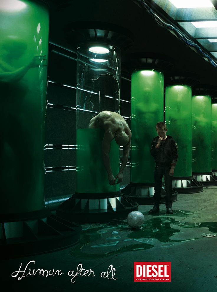 a man standing next to a green wall in a room filled with urinals